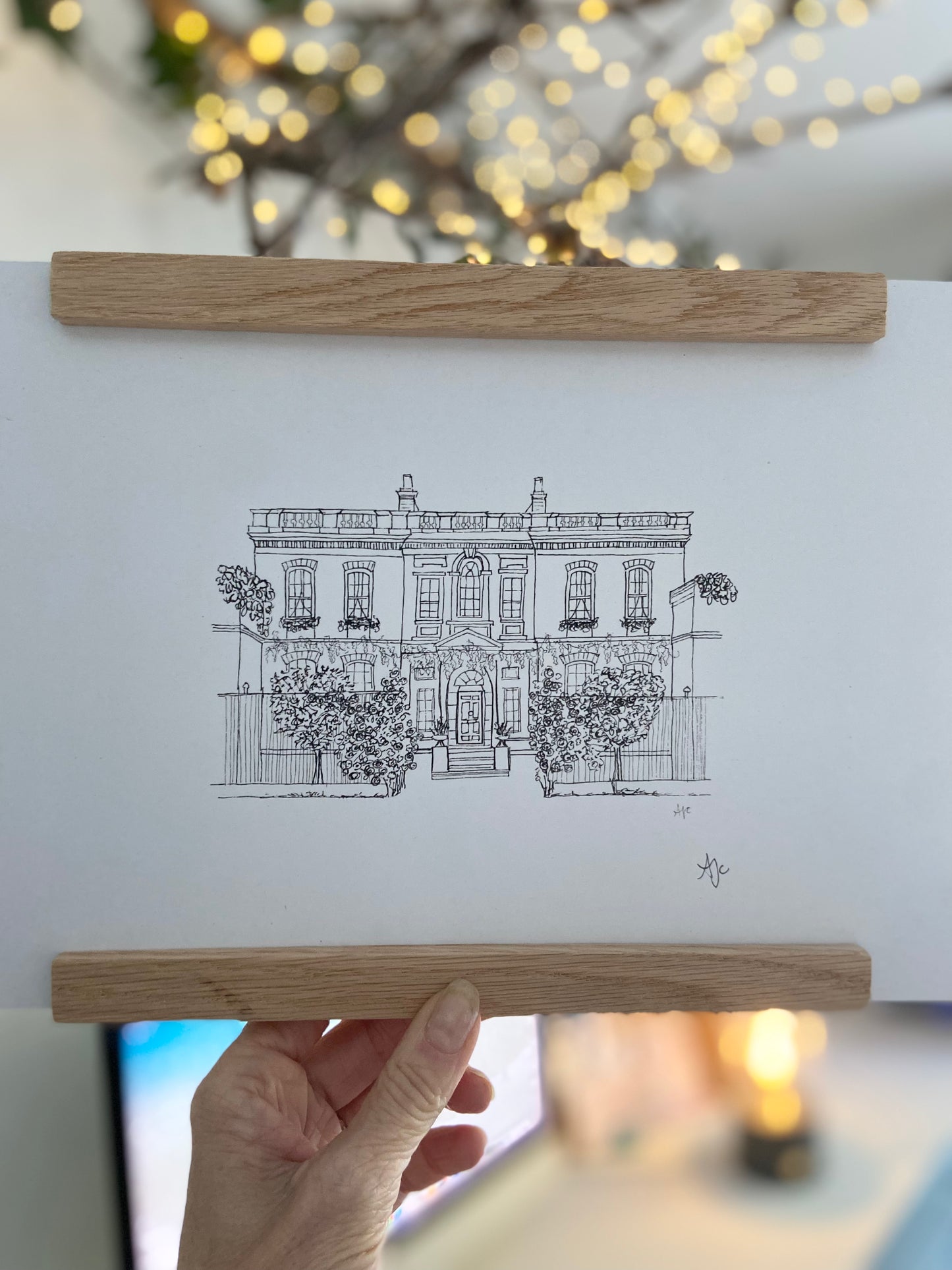 Bridgerton House print in a bamboo frame being held by hand.