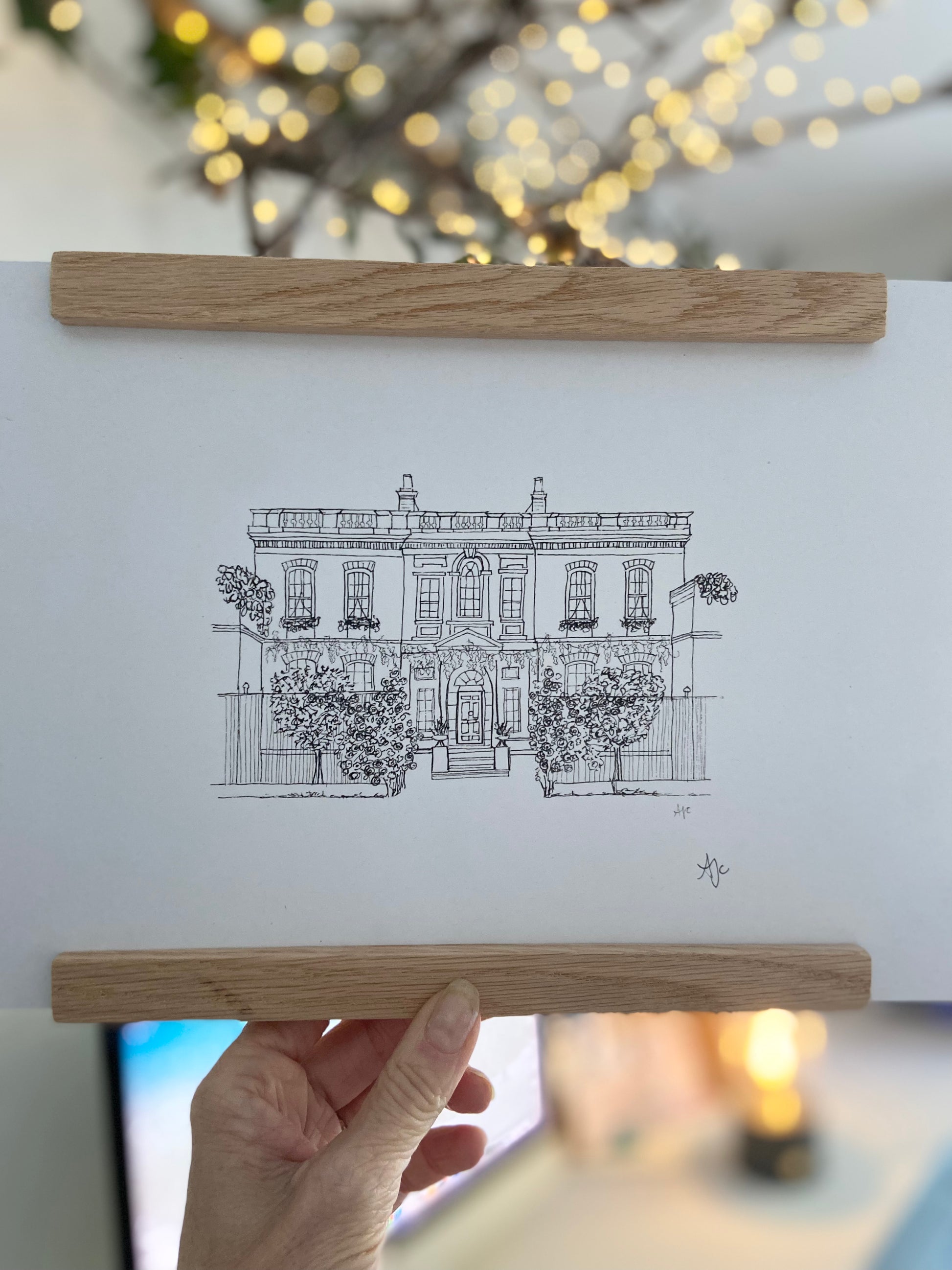 Bridgerton House print in a bamboo frame being held by hand.