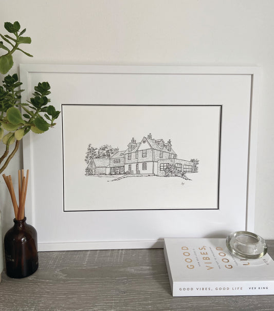 A framed hand-drawn illustration of a house, double mounted with a white frame.