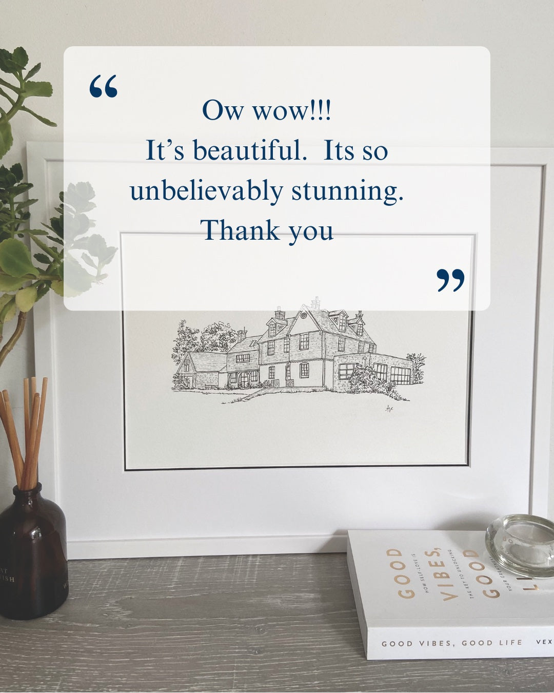 Framed black and white house illustration with decorative elements on a shelf.