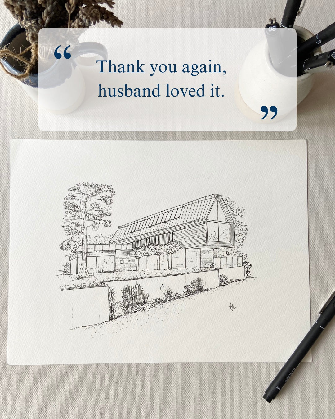 Note card with house illustration and text 'Thank you again, husband loved it.' on a textured surface.